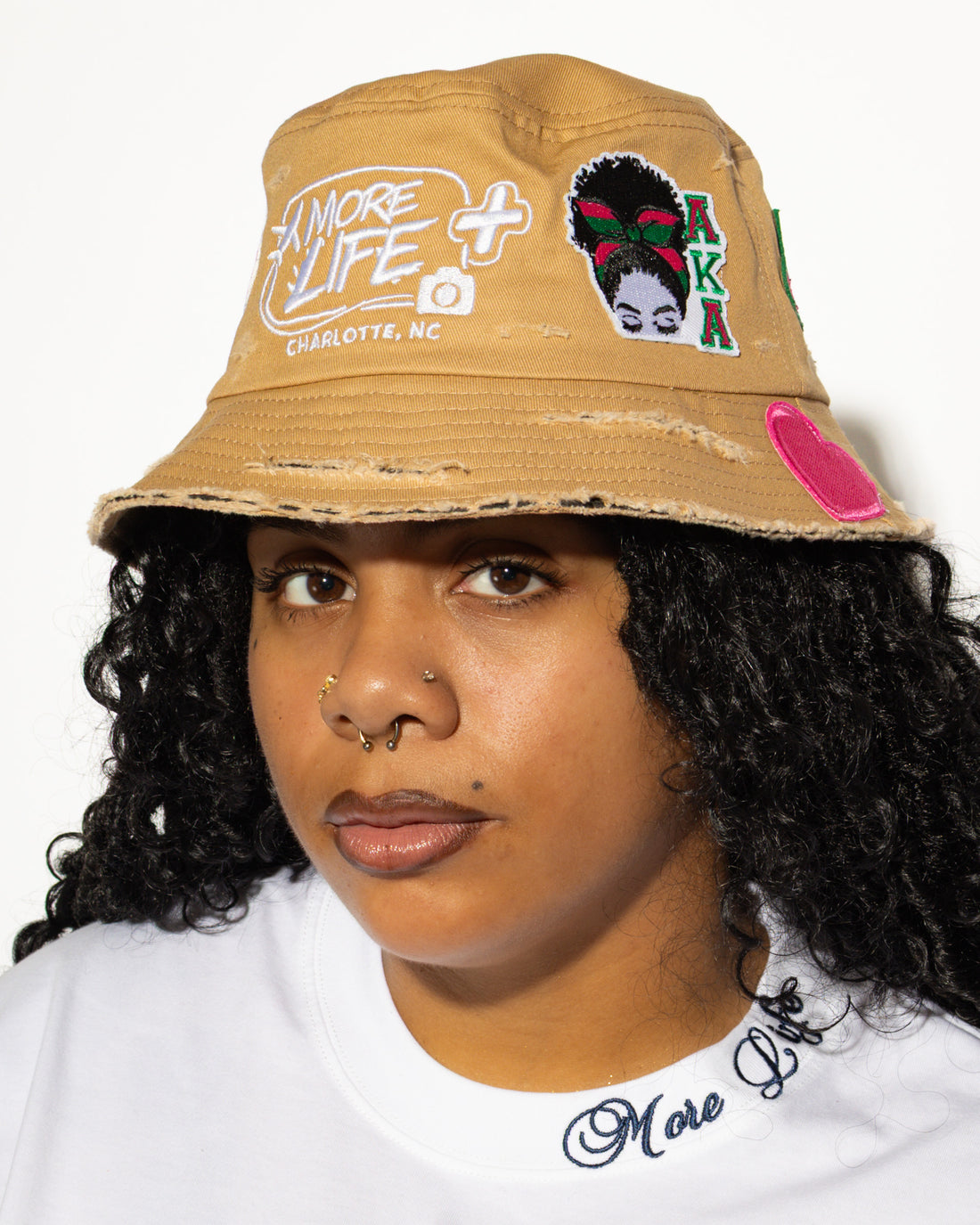 More Life CLT AKA Sorority Patchwork Distressed Bucket Hat Tan – front view on model showing More Life Charlotte NC logo and AKA butterfly woman patch
