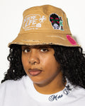 More Life CLT AKA Sorority Patchwork Distressed Bucket Hat Tan – front view on model showing More Life Charlotte NC logo and AKA butterfly woman patch