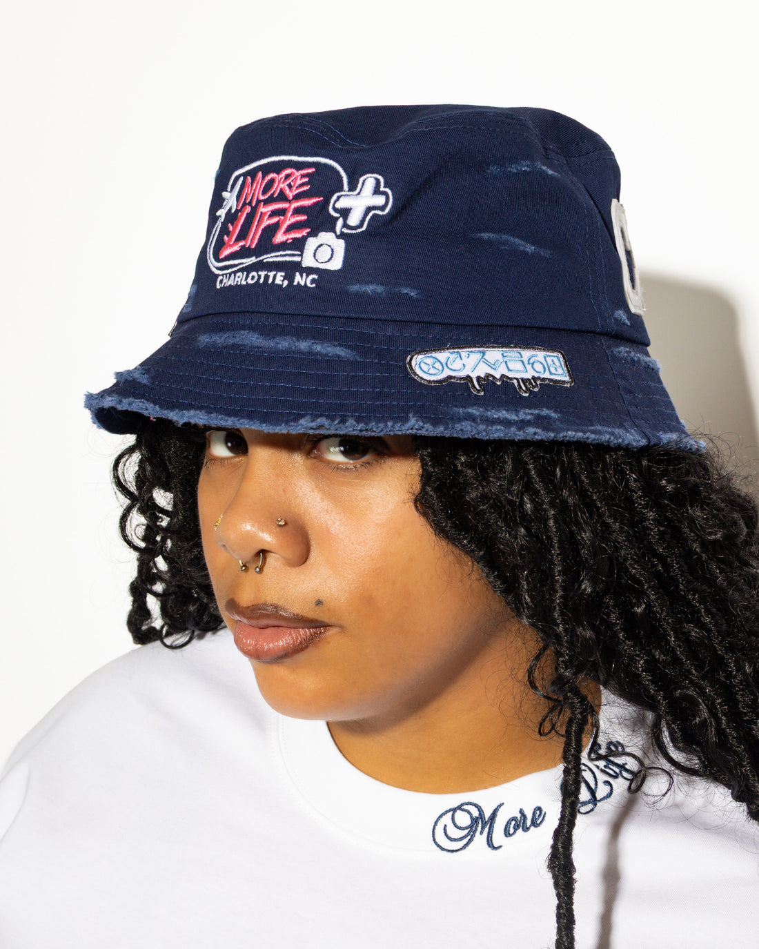 More Life CLT CB Breezy Bowl Stadium Tour Patchwork Distressed Bucket Hat Navy Blue – front view on model showing More Life Charlotte NC logo and graffiti drip tab patch