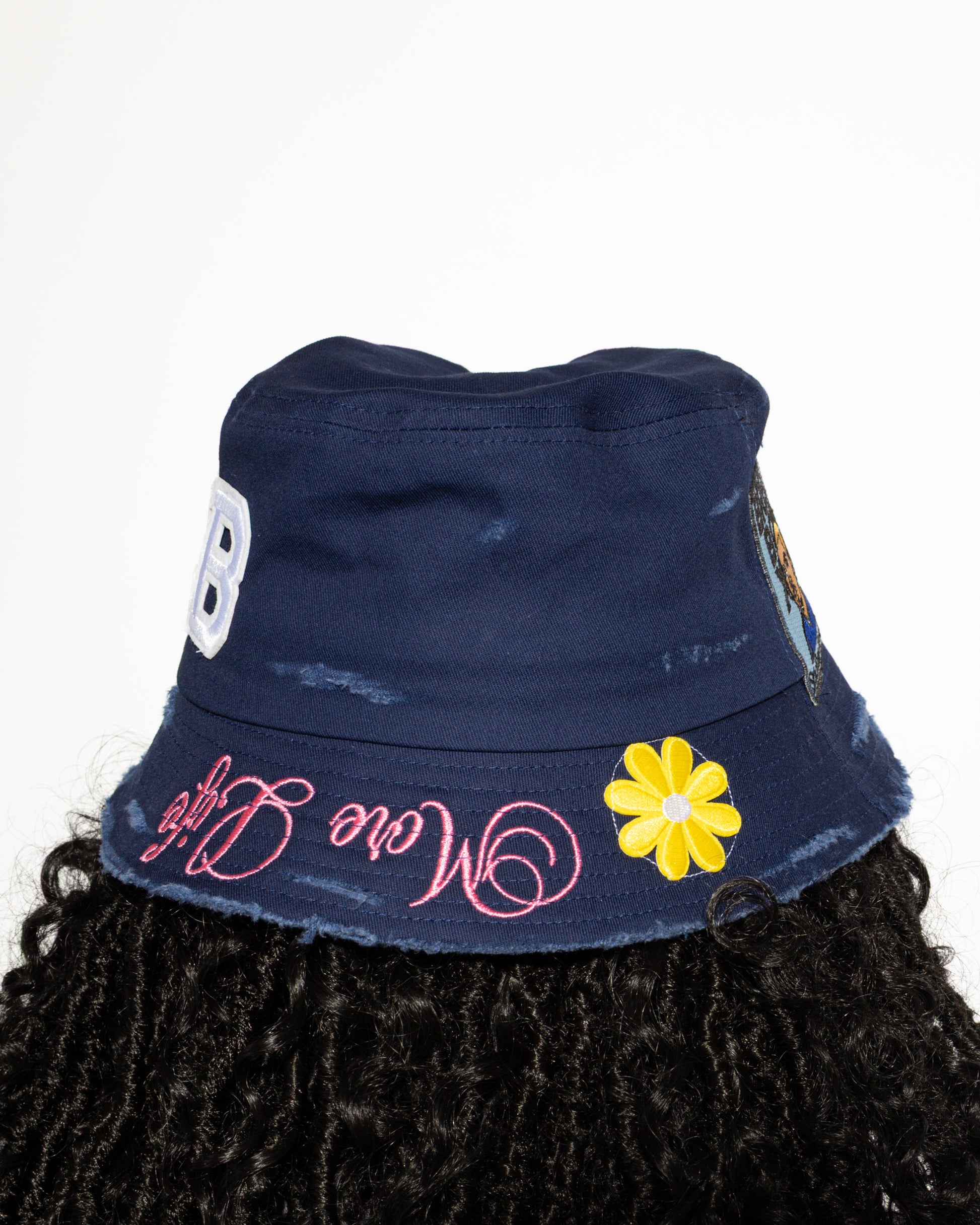 More Life CLT CB Breezy Bowl Stadium Tour Patchwork Distressed Bucket Hat Navy Blue – back view showing CB varsity letters patch yellow daisy flower and More Life pink brim embroidery