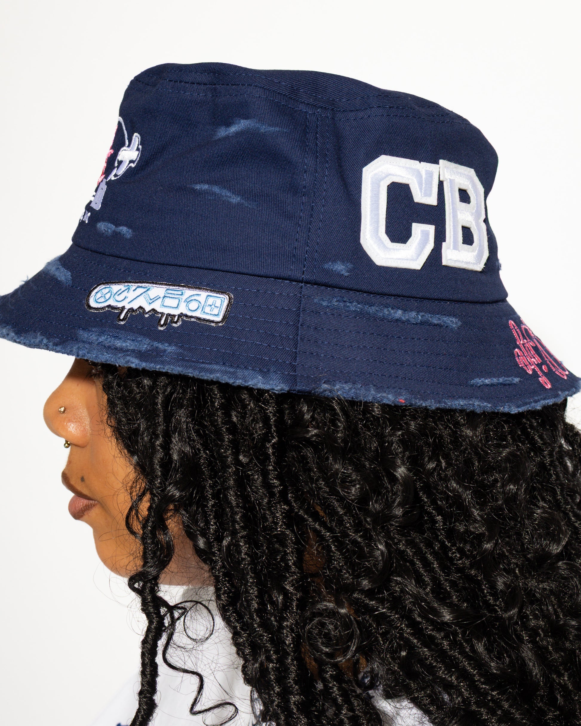 More Life CLT CB Breezy Bowl Stadium Tour Patchwork Distressed Bucket Hat Navy Blue – side view on model showing CB varsity letters patch and graffiti drip tab on brim