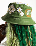 More Life CLT Custom Deluxe Bucket Hat Green – top view showing full daisy flower patch coverage on olive green distressed base