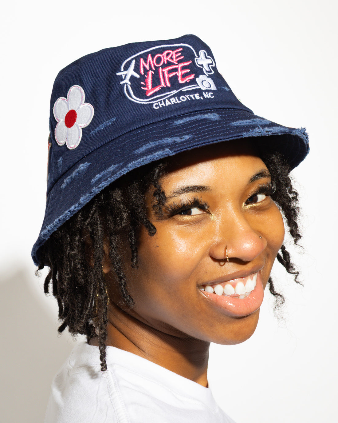 More Life CLT Charlotte Patchwork Distressed Bucket Hat Navy Blue – side view showing More Life Charlotte NC logo and daisy flower patch