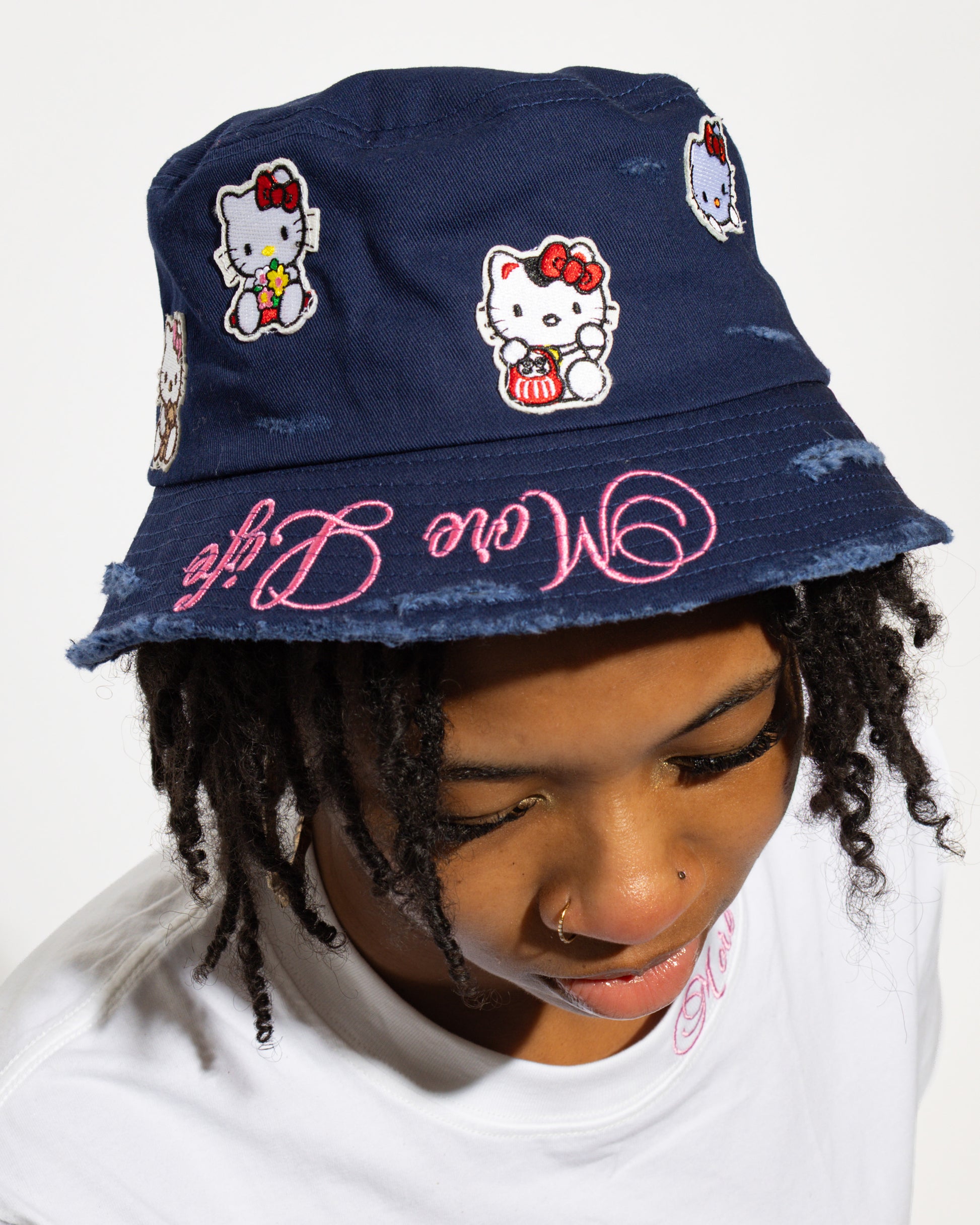 More Life CLT Hello Kitty Patchwork Distressed Bucket Hat Navy Blue – front view on model showing Hello Kitty patches and pink More Life brim embroidery