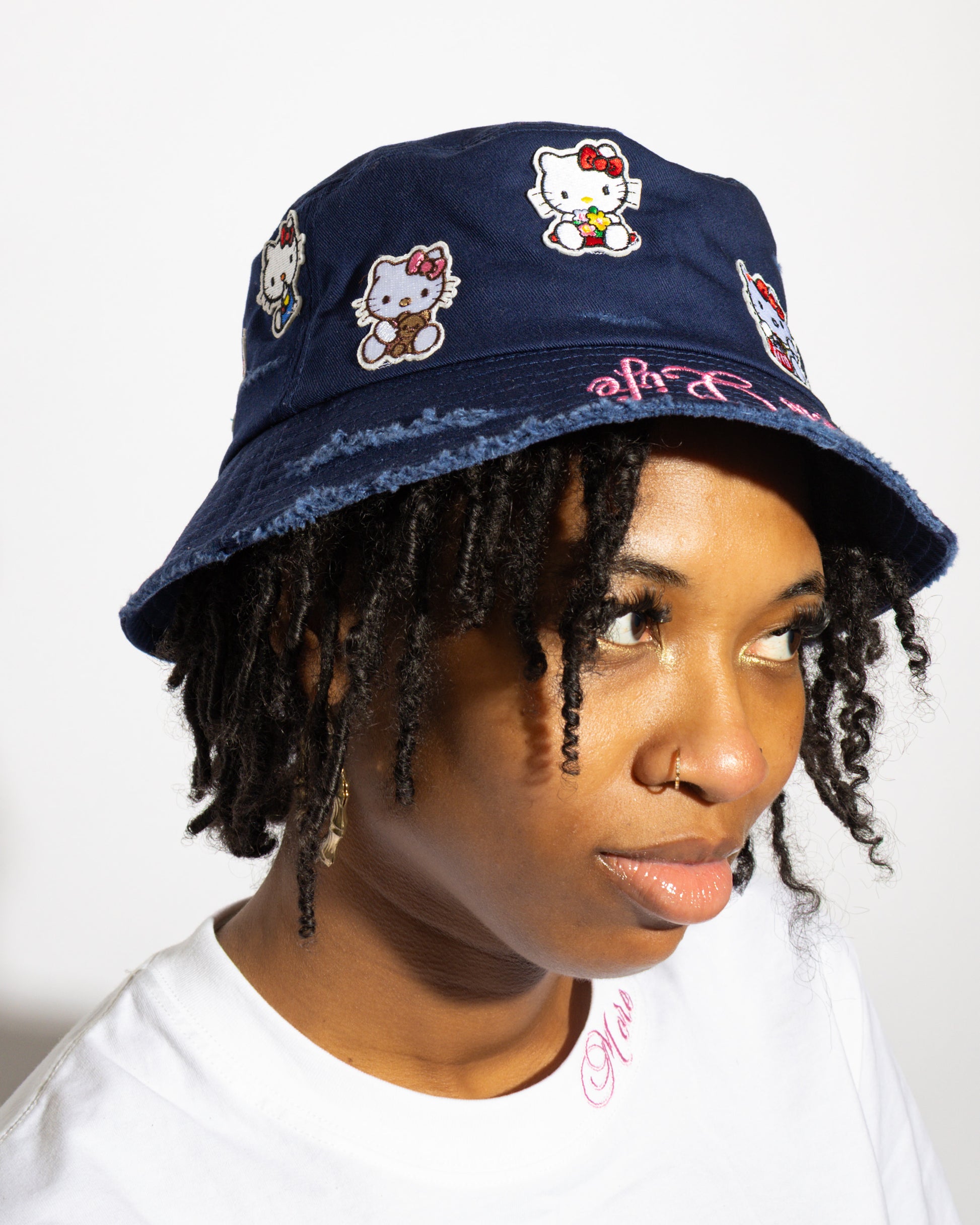 More Life CLT Hello Kitty Patchwork Distressed Bucket Hat Navy Blue – side view on model showing multiple Hello Kitty character patches