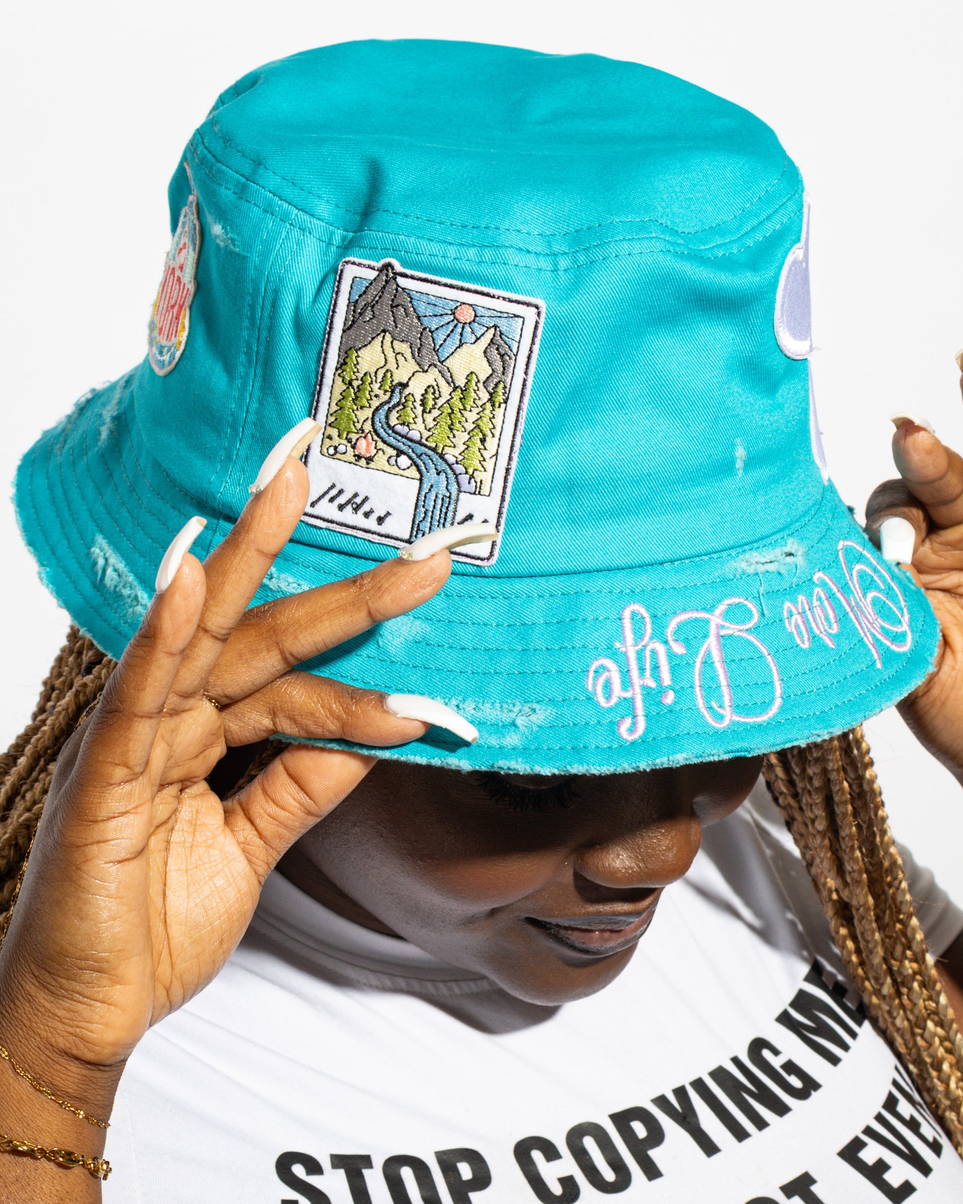 More Life CLT Daisy New York Patchwork Distressed Bucket Hat Teal – back view on model showing mountain landscape polaroid patch and More Life brim embroidery